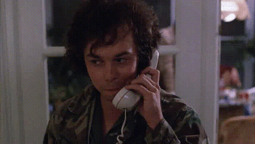 A Man In A Camo Shirt Is Talking On A Telephone GIF