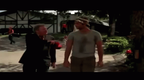 A Man In A Camouflage Hat Talks To Another Man In A White Shirt GIF