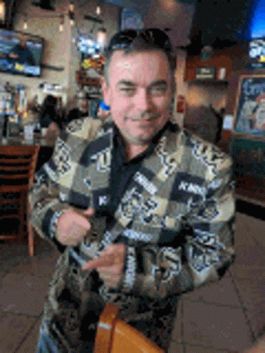A Man In A Camouflage Jacket Is Standing In A Restaurant . GIF