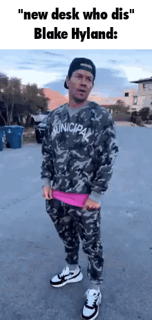 A Man In A Camouflage Shirt And Pants Is Standing On A Street . GIF