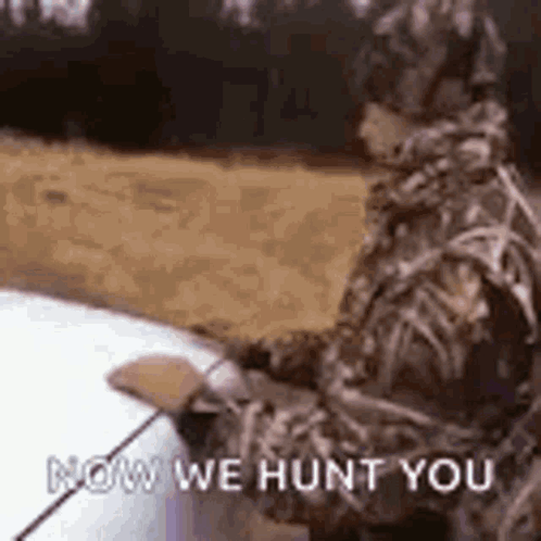 A Man In A Camouflage Suit Is Standing Next To A Car Holding A Fishing Rod And A Fishing Pole . GIF
