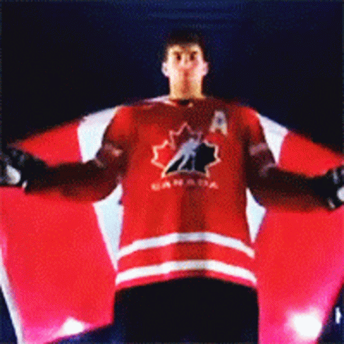 a man in a canada jersey is holding a large canadian flag