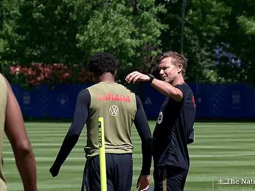 A Man In A Canada Jersey Talks To Another Man On A Field GIF