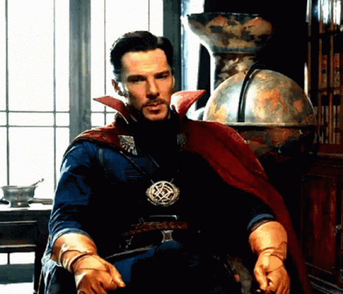 A Man In A Cape And Gloves Is Sitting In Front Of A Window . GIF