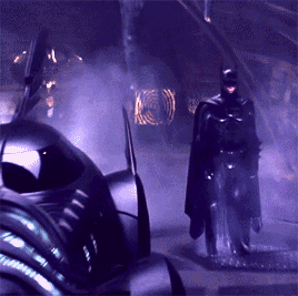 A Man In A Cape Is Standing In Front Of A Purple Car GIF