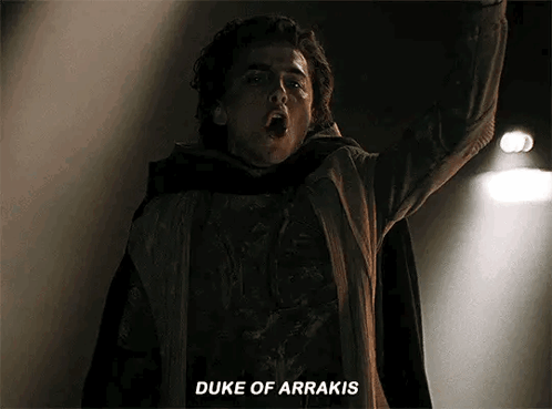A Man In A Cape Is Standing In The Dark With His Arms In The Air And Says `` Duke Of Arrakis '' . GIF