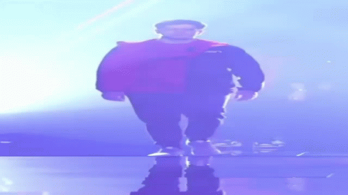 A Man In A Cape Is Walking On A Stage In The Dark GIF