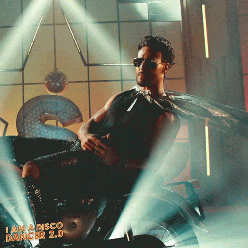 A Man In A Cape Sits On A Motorcycle With The Words I Am A Disco Dancer 2.0 On The Bottom GIF