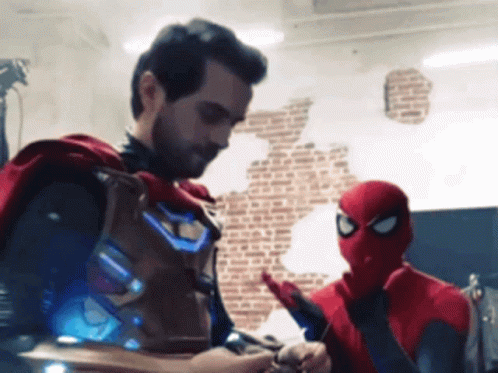 A Man In A Cape Stands Next To A Man In A Spider Man Costume GIF