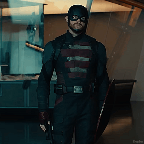 A Man In A Captain America Costume Holds A Shield And A Gun GIF