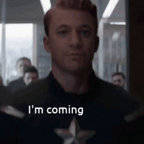 A Man In A Captain America Costume Is Saying `` I 'M Coming '' In Front Of A Crowd Of People . GIF