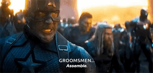 A Man In A Captain America Costume Is Standing In Front Of A Crowd Of People . GIF