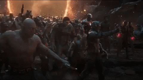A Man In A Captain America Costume Stands In Front Of A Crowd Of People GIF