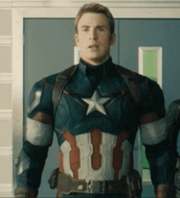 A Man In A Captain America Suit Is Standing In Front Of A Door . GIF