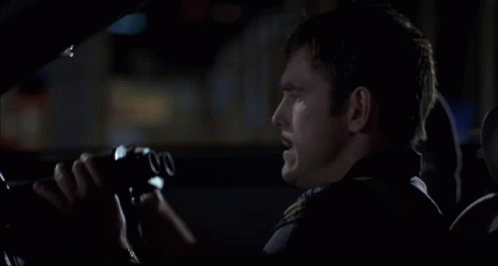 A Man In A Car Is Looking Through Binoculars With The Number 00 On The Lens GIF