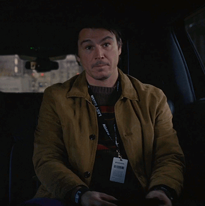 A Man In A Car With A Lanyard Around His Neck That Says ' Kevin A. Scott ' GIF