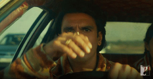 A Man In A Car With A Ring On His Finger Looks At The Camera GIF