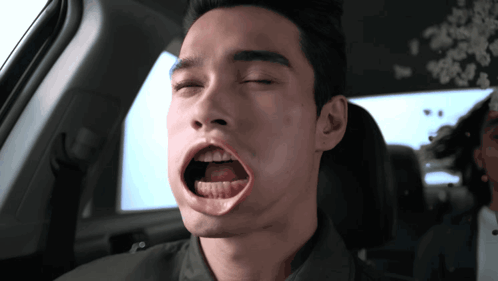 A Man In A Car With His Eyes Closed And His Mouth Open GIF