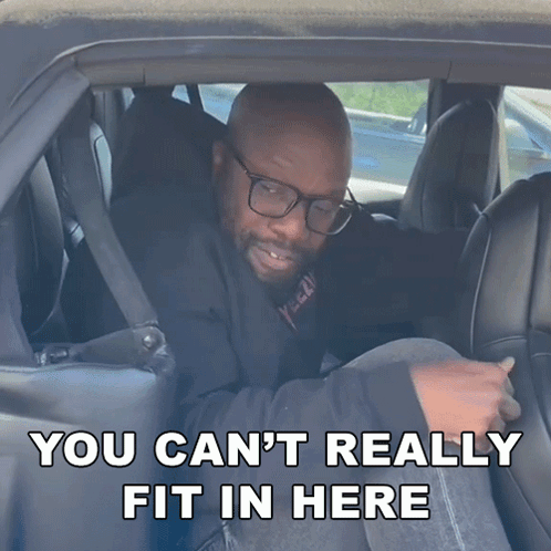 A Man In A Car With The Words " You Can T Really Fit In Here " GIF