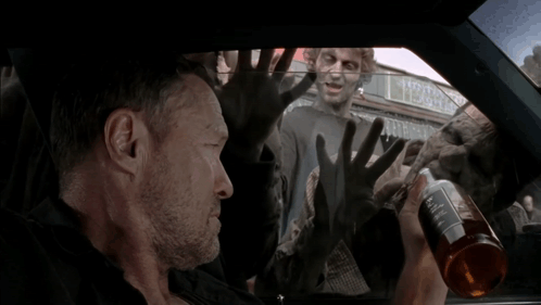 A Man In A Car With Zombies Behind Him And A Sign That Says Tobacco On It GIF