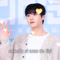 A Man In A Cardigan Is Waving His Hand In Front Of A Sign That Says Saluda Si Eres De Fist GIF