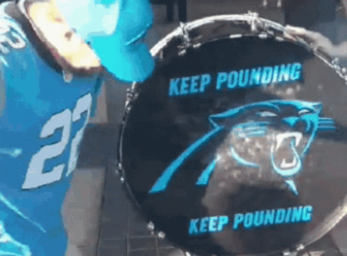 A Man In A Carolina Panthers Jersey Is Playing A Drum GIF