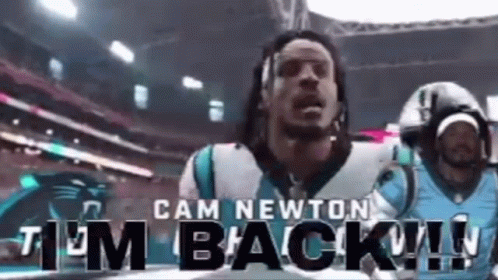 A Man In A Carolina Panthers Jersey Is Standing In A Stadium . GIF