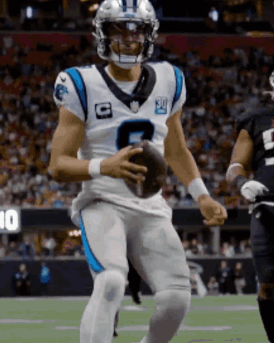 a man in a carolina panthers uniform holds a football