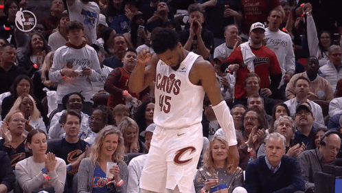 A Man In A Cavs Jersey Stands In Front Of A Crowd Of People GIF