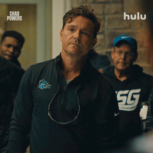 A Man In A Chad Powers Shirt Stands In Front Of A Hulu Logo GIF