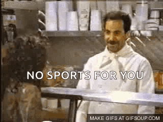 A Man In A Chef 'S Coat Is Standing In A Kitchen Talking To A Woman . GIF