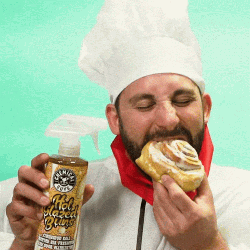 A Man In A Chef 'S Hat Is Eating A Cinnamon Roll While Holding A Bottle Of Chemical Guys GIF