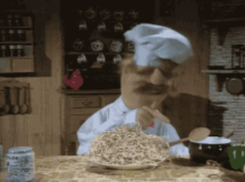 A Man In A Chef 'S Hat Is Eating Noodles With A Fork GIF