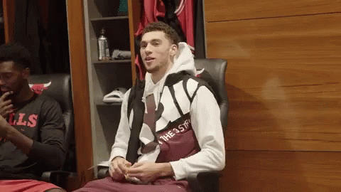 A Man In A Chicago Bulls Shirt Sits In A Chair In A Locker Room GIF