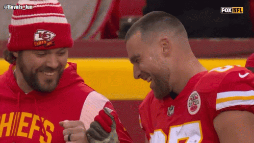 a man in a chiefs shirt laughs with another man