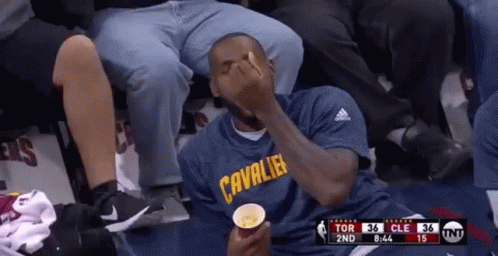 A Man In A Cleveland Cavaliers Shirt Is Sitting In A Stadium Eating Popcorn . GIF