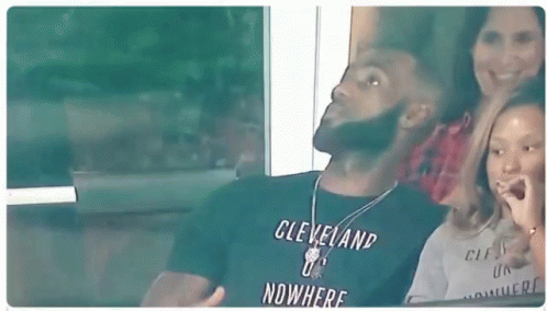 A Man In A Cleveland T-Shirt Is Sitting In A Stadium With A Woman And A Child . GIF
