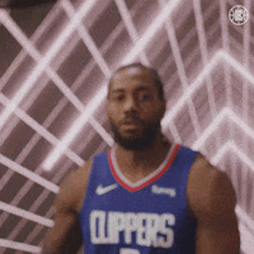 A Man In A Clippers Jersey Is Standing In Front Of A Wall With Lights Behind Him . GIF