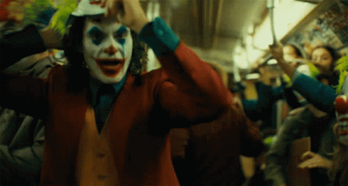 A Man In A Clown Costume Is Holding A Baseball Cap GIF