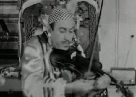 A Man In A Clown Costume Is Playing A Violin . GIF