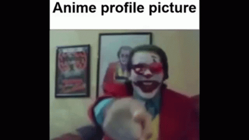 A Man In A Clown Costume Is Pointing At The Camera In Front Of A Picture Of The Joker . GIF