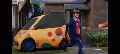 A Man In A Clown Costume Is Running Away From A Yellow Car That Says Taxi GIF