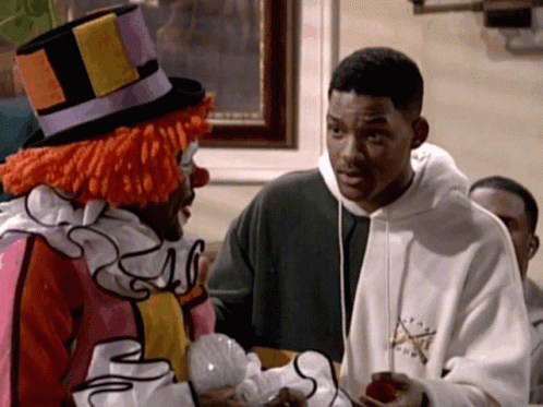A Man In A Clown Costume Is Talking To Another Man GIF