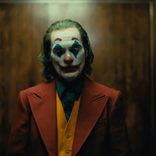 A Man In A Clown Costume Is Wearing A Red Suit And A Yellow Vest GIF