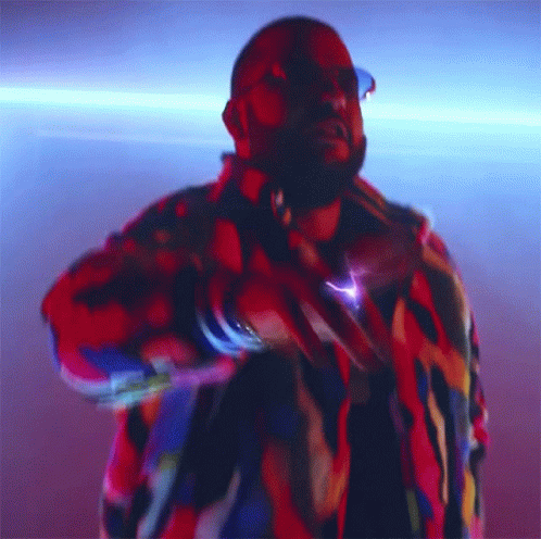 A Man In A Colorful Jacket Is Dancing In A Dark Room GIF