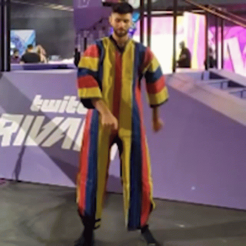 A Man In A Colorful Robe Is Standing In Front Of A Purple Wall That Says Rival GIF