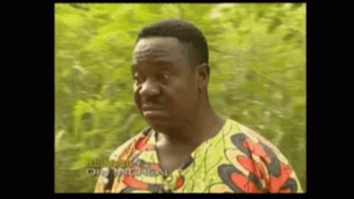 A Man In A Colorful Shirt Is Making A Funny Face While Standing In Front Of A Tree . GIF