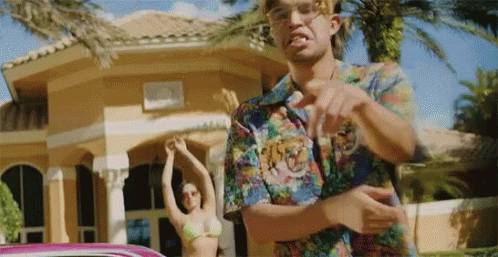 A Man In A Colorful Shirt Is Pointing At A Woman In A Bikini . GIF
