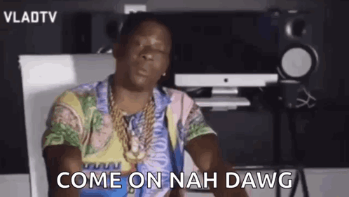 A Man In A Colorful Shirt Is Sitting In Front Of A Computer And A Microphone . GIF