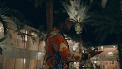 A Man In A Colorful Shirt With The Word Gucci On The Back GIF